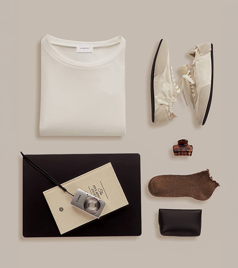 styled flat lay with folded white t-shirt shoes and accessories on beige background for product photography
