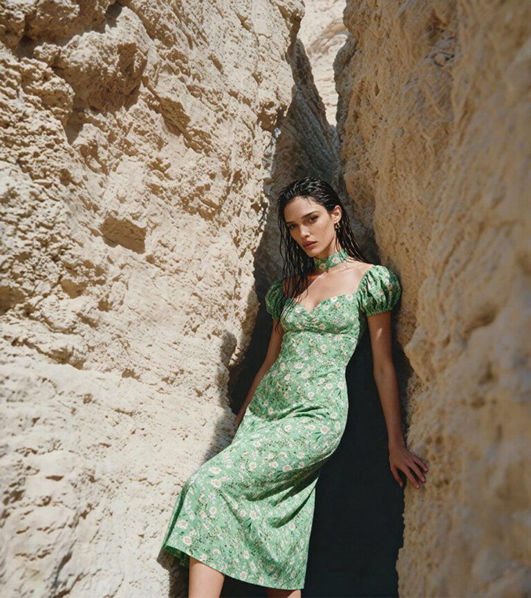 fashion model in green floral midi dress standing in desert rock canyon for fashion ecommerce photography