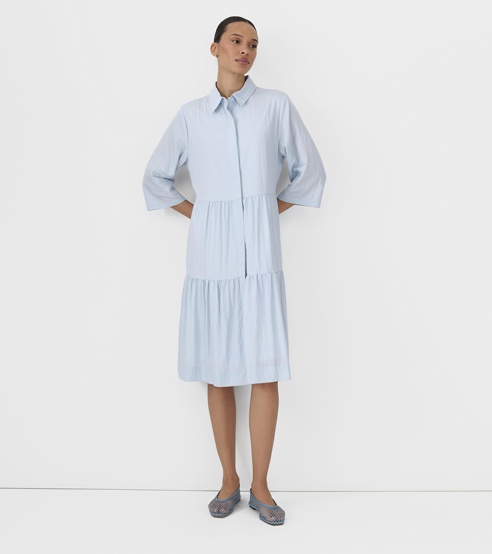 fashion model in light blue tiered shirt dress on white studio background for ecommerce product photography