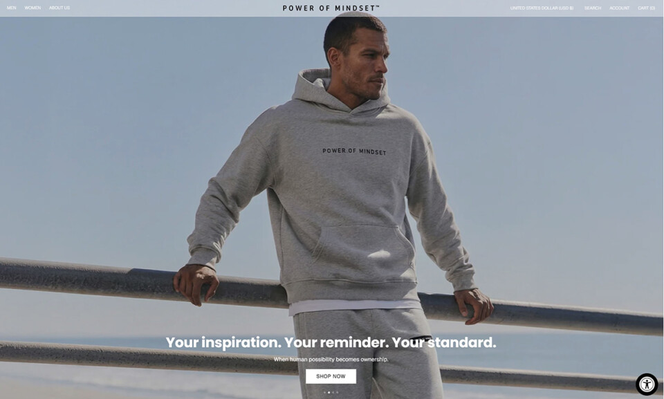 AI models for ecommerce products by Shootify. Power of Mindset homepage banner with male model in a grey hoodie leaning on a railing by the sea.