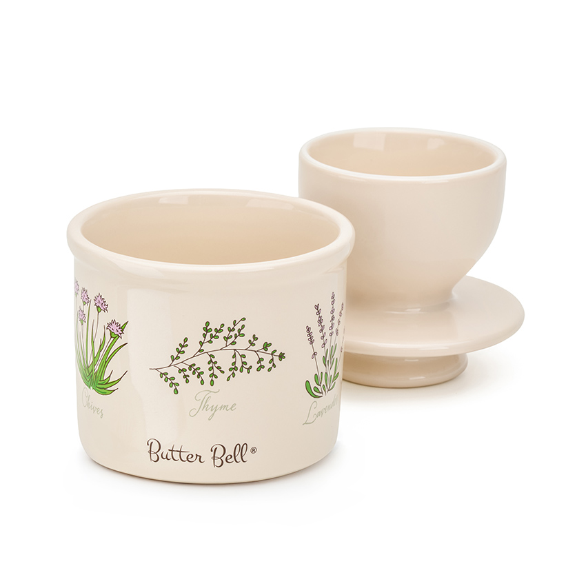 Product photography of a ceramic butter crock base with its bell lid standing upside down beside it