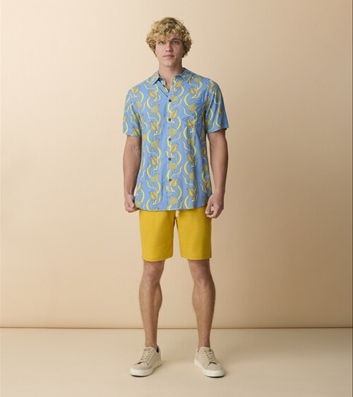Male model wearing blue tropical print shirt and yellow shorts on a model product photography