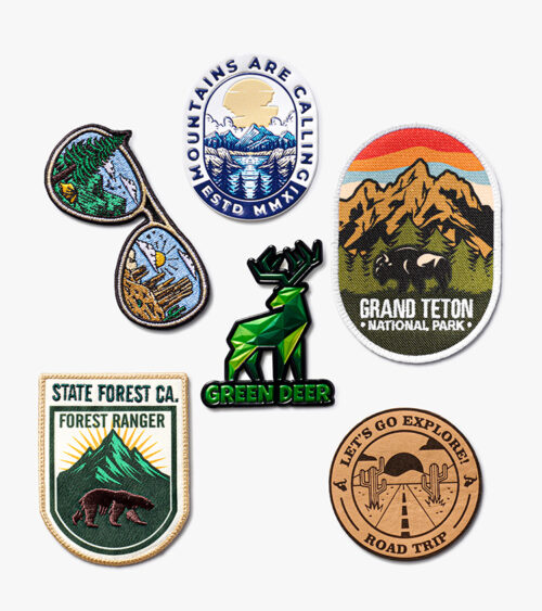 Product photography of an outdoor-themed collection of embroidered and woven patches with an enamel pin, grouped on white.