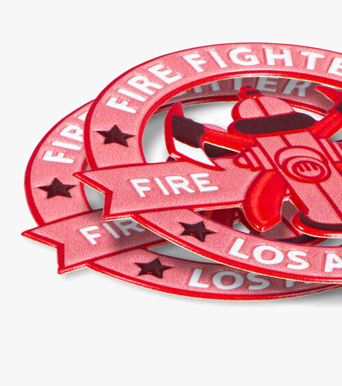 Macro detail photography of red firefighter emblem patches highlighting raised texture and lettering.