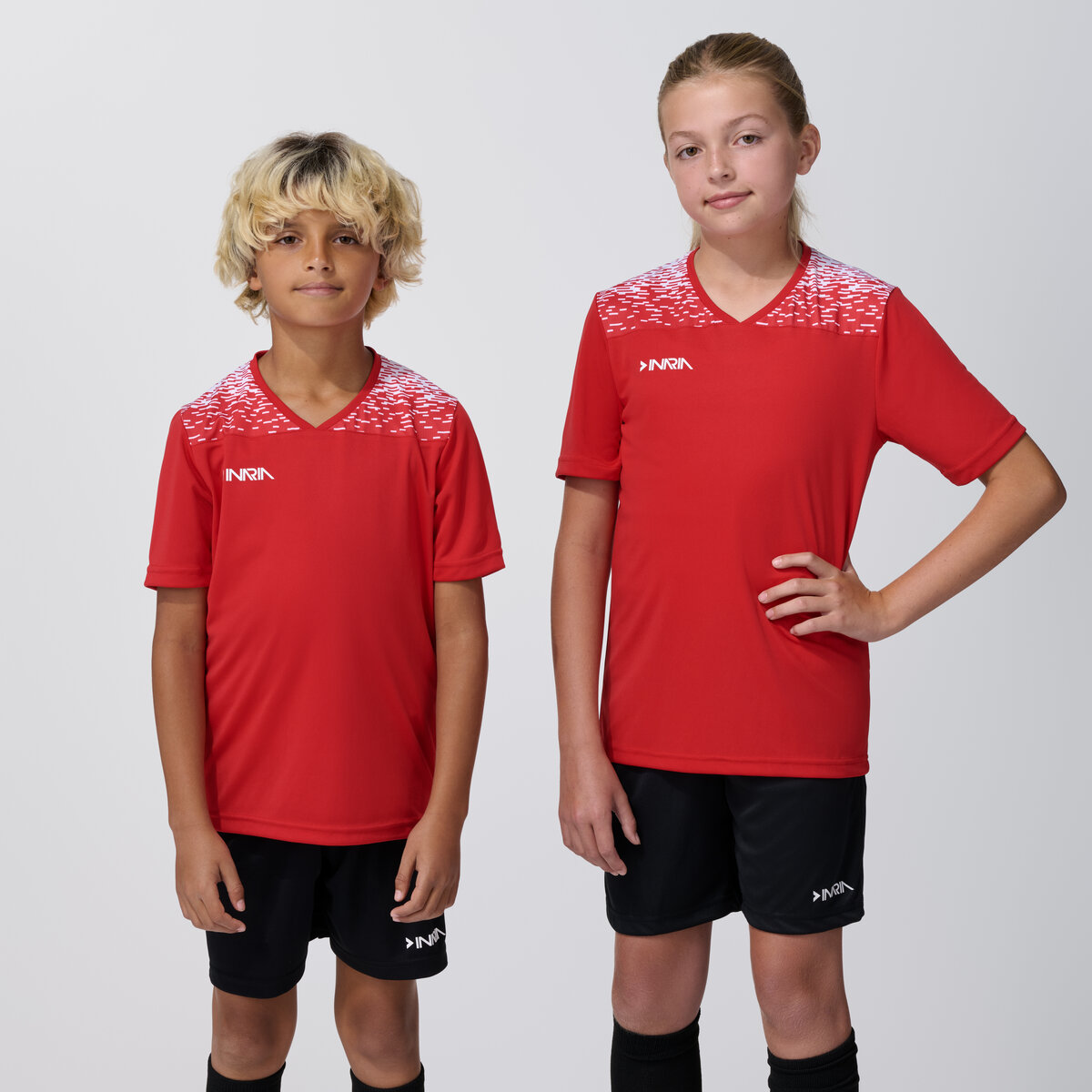 Two youth models in matching red soccer jerseys and shorts, on-model team uniform photography