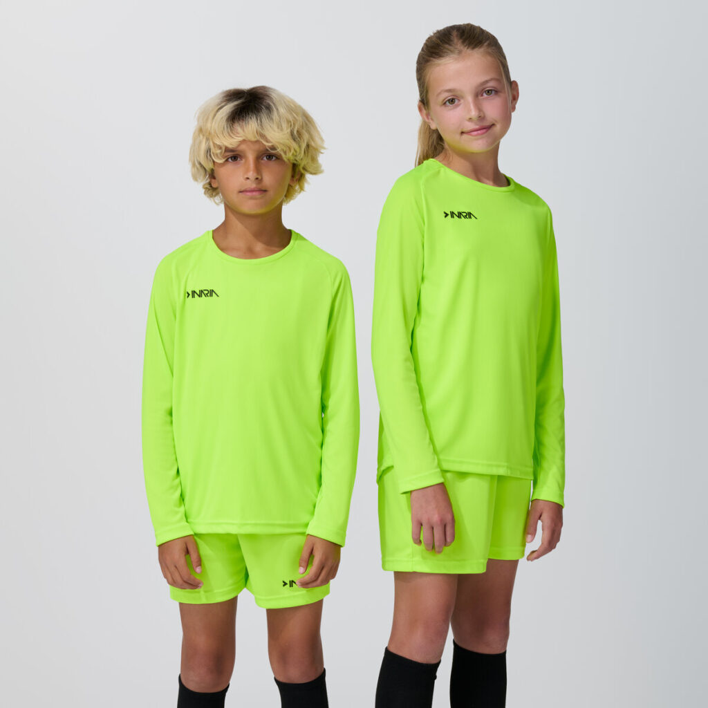 Two youth models in matching neon yellow-green long sleeve soccer jerseys