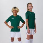 Two youth models in matching dark green soccer jerseys and white shorts