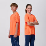 Two teen models in matching orange soccer jerseys, arms crossed