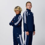 Two teen models in matching navy adidas tracksuits with white stripes