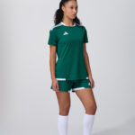Female model in dark green soccer jersey with white shorts and socks