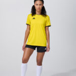 Female model in yellow soccer jersey and black shorts