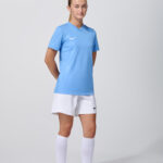 Female model in light blue soccer jersey and white shorts