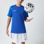 Male model in blue Nike soccer jersey holding a soccer ball