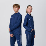 Two youth models in matching navy Nike track jackets and pants
