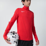 Male model in red Nike long sleeve jacket holding a soccer ball
