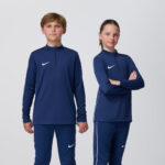 Two youth models in matching navy Nike quarter-zip tops and pants