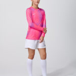 Female model in pink long sleeve soccer jersey and white shorts