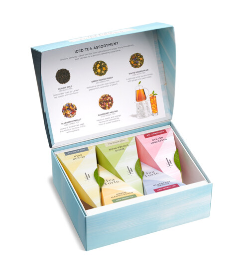 eCommerce product photography of a Tea Forte gift collection with assorted tea blends in premium packaging for a luxury tea brand website.