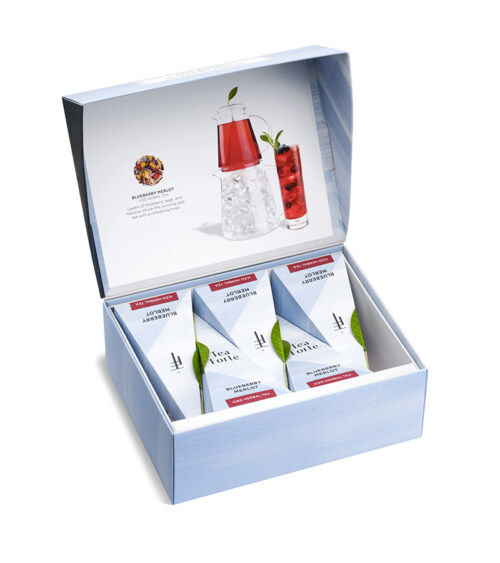 Luxury product photography of a Tea Forte gift box with assorted tea pyramids and tea bottle on a white background for an eCommerce product listing.