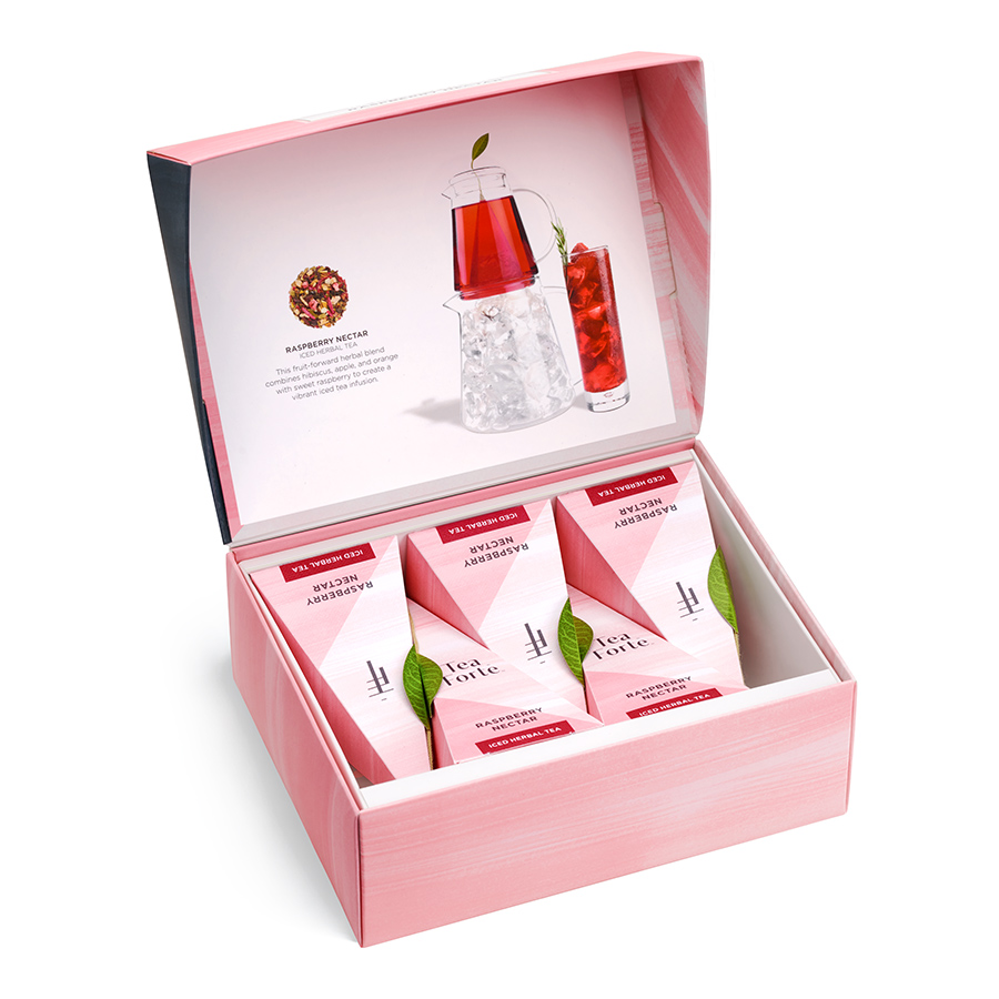 White background product photography of an open pink Tea Forté Raspberry Nectar box with three inner packages and printed lid artwork