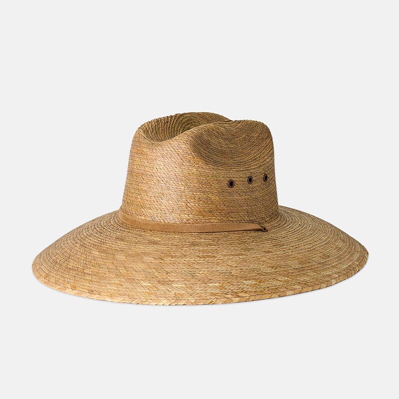 Product photography of a wide-brim woven palm straw sun hat with a tan band, three-quarter view on white