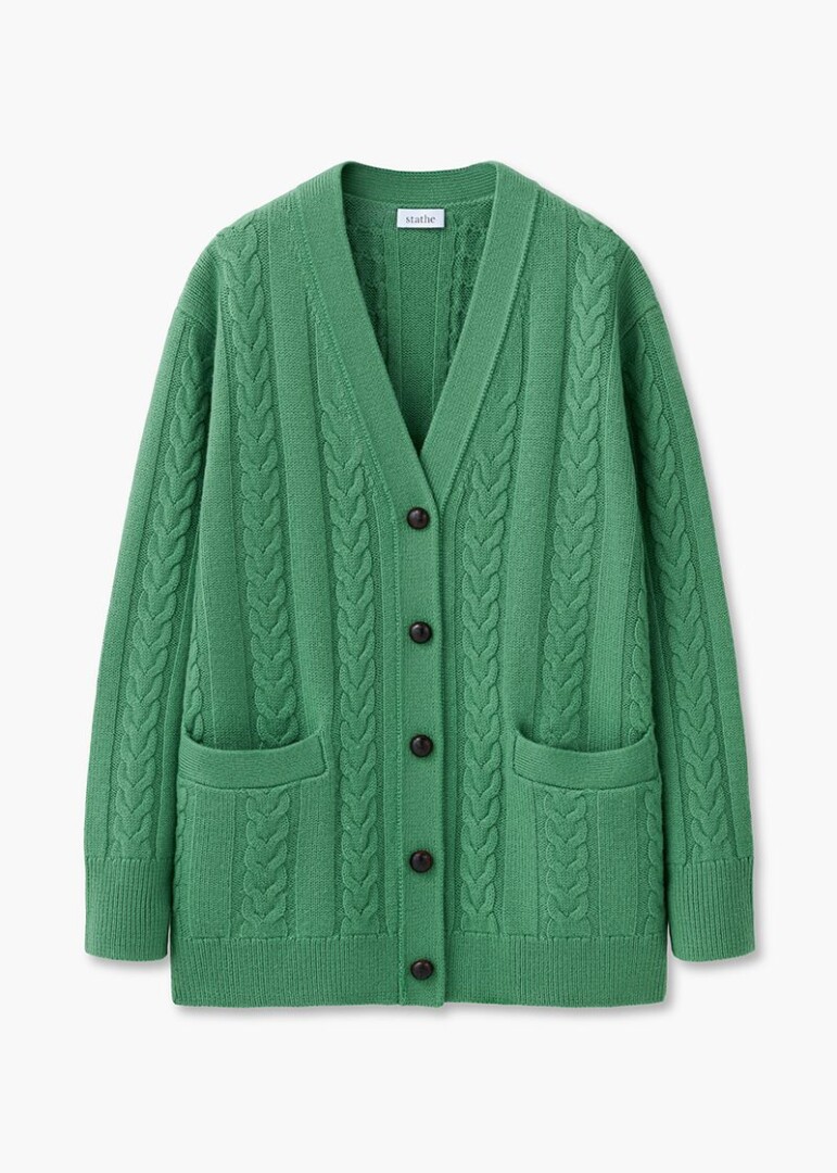 Flat lay product photography of a green cable-knit button-front cardigan with patch pockets, front view on white