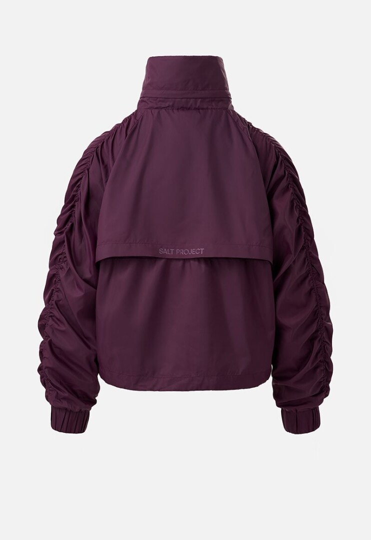 Product photography of a plum windbreaker jacket, back view showing the storm flap and printed brand name