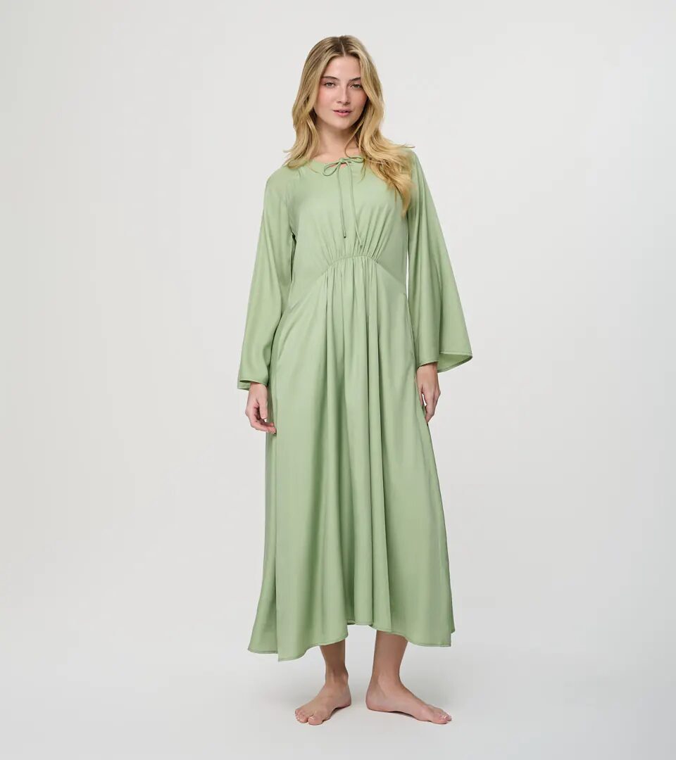 On-model photography of a sage green gathered-waist maxi dress with wide sleeves, full-length front view on a light grey background
