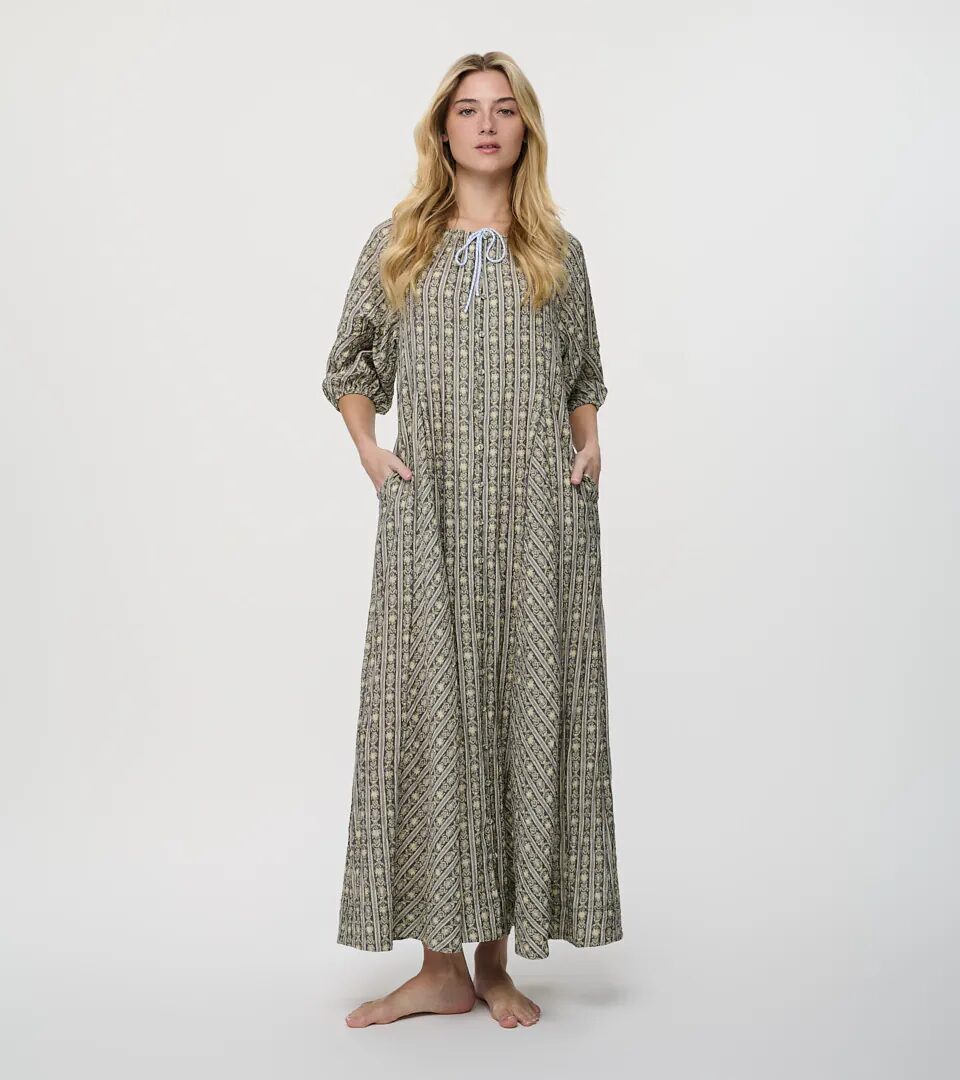 On-model photography of a green and cream block-printed maxi dress with a drawstring neckline and side pockets, full-length front view