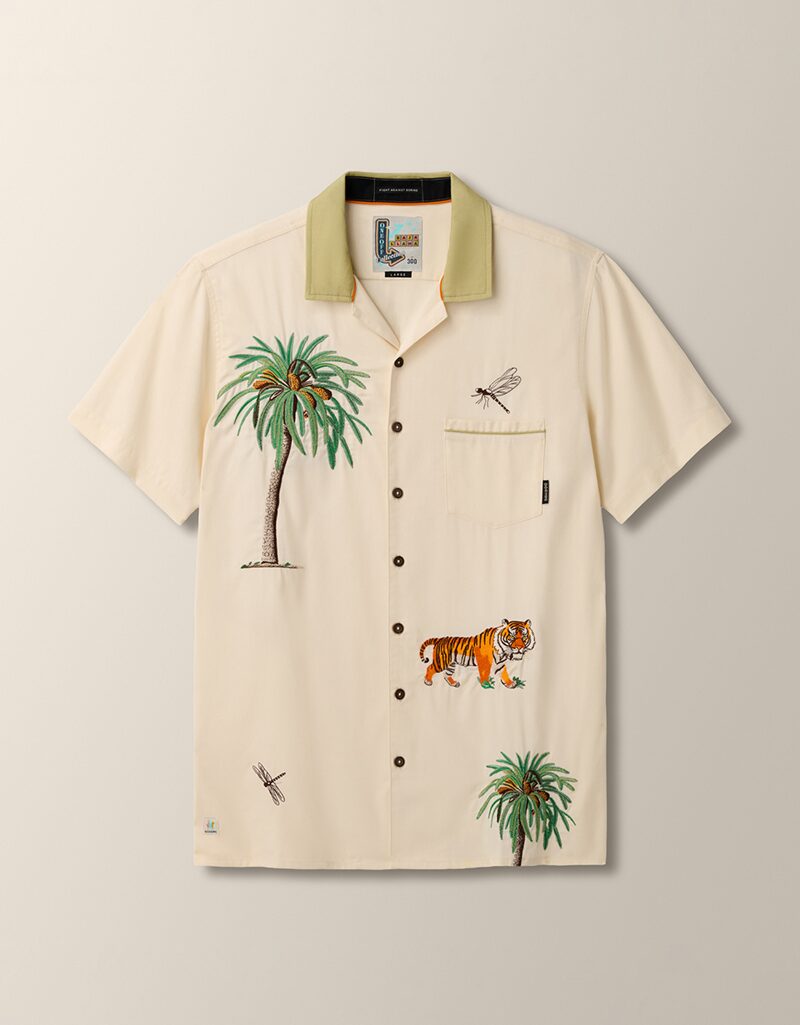 Flat lay product photography of a cream camp-collar shirt with a green contrast collar and embroidered palm trees, tiger and dragonflies, front view