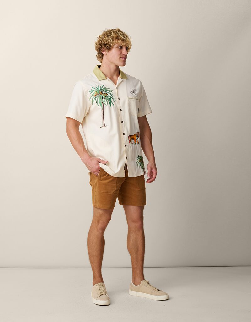 On-model photography of a cream embroidered camp-collar shirt worn with tan corduroy shorts, full-length front view