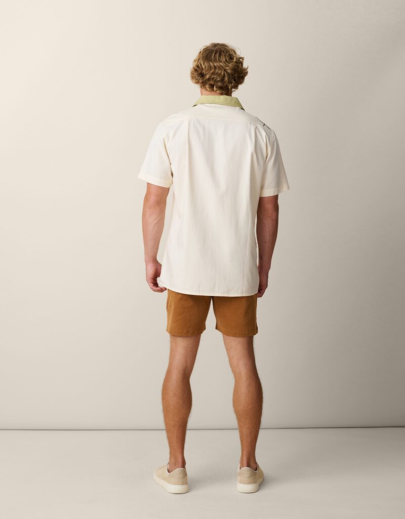 On-model photography of a cream embroidered camp-collar shirt, full-length back view showing the plain back and curved hem