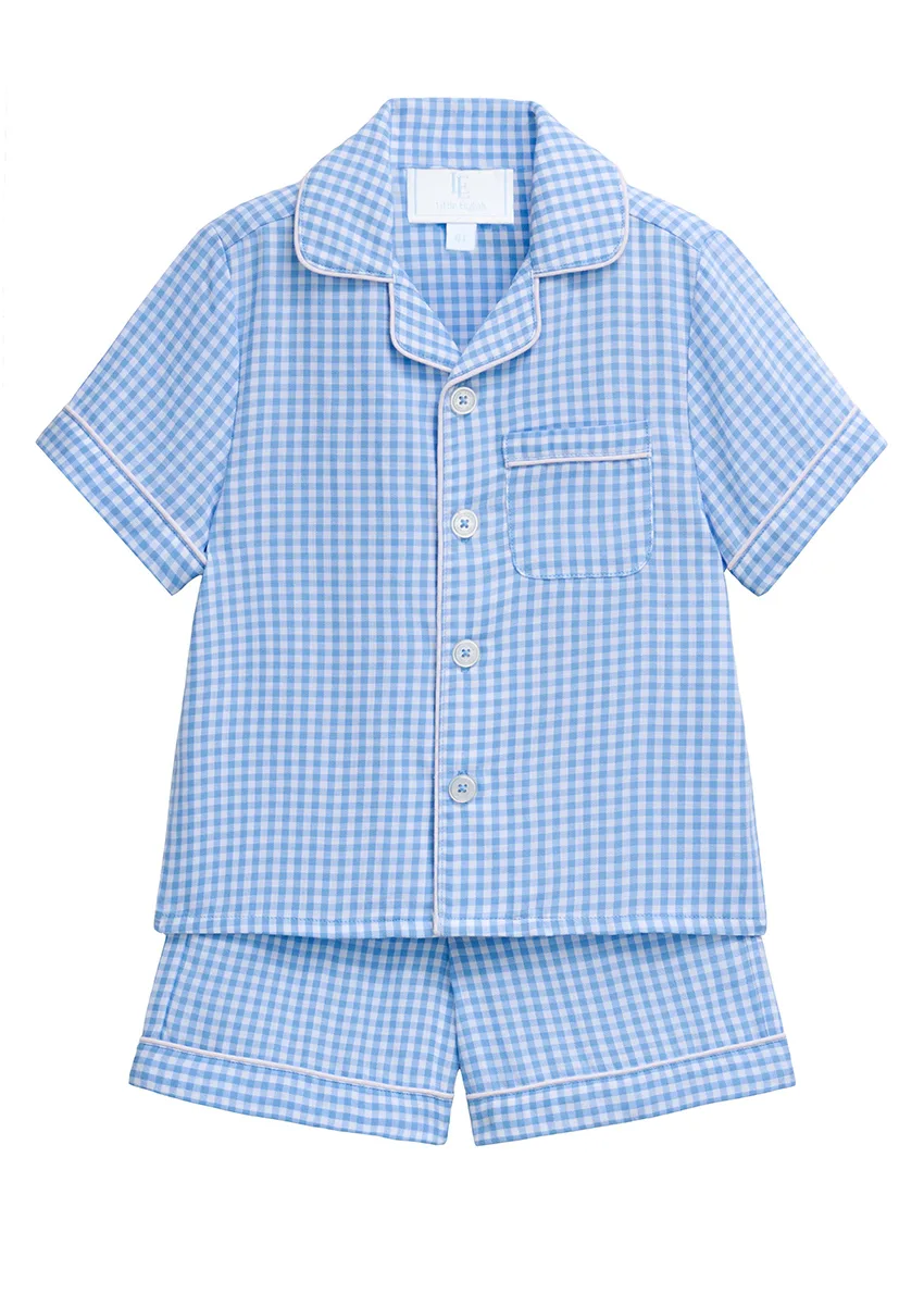 Blue gingham boys' pajama set with white piping and chest pocket, shirt and shorts styled flat lay on white