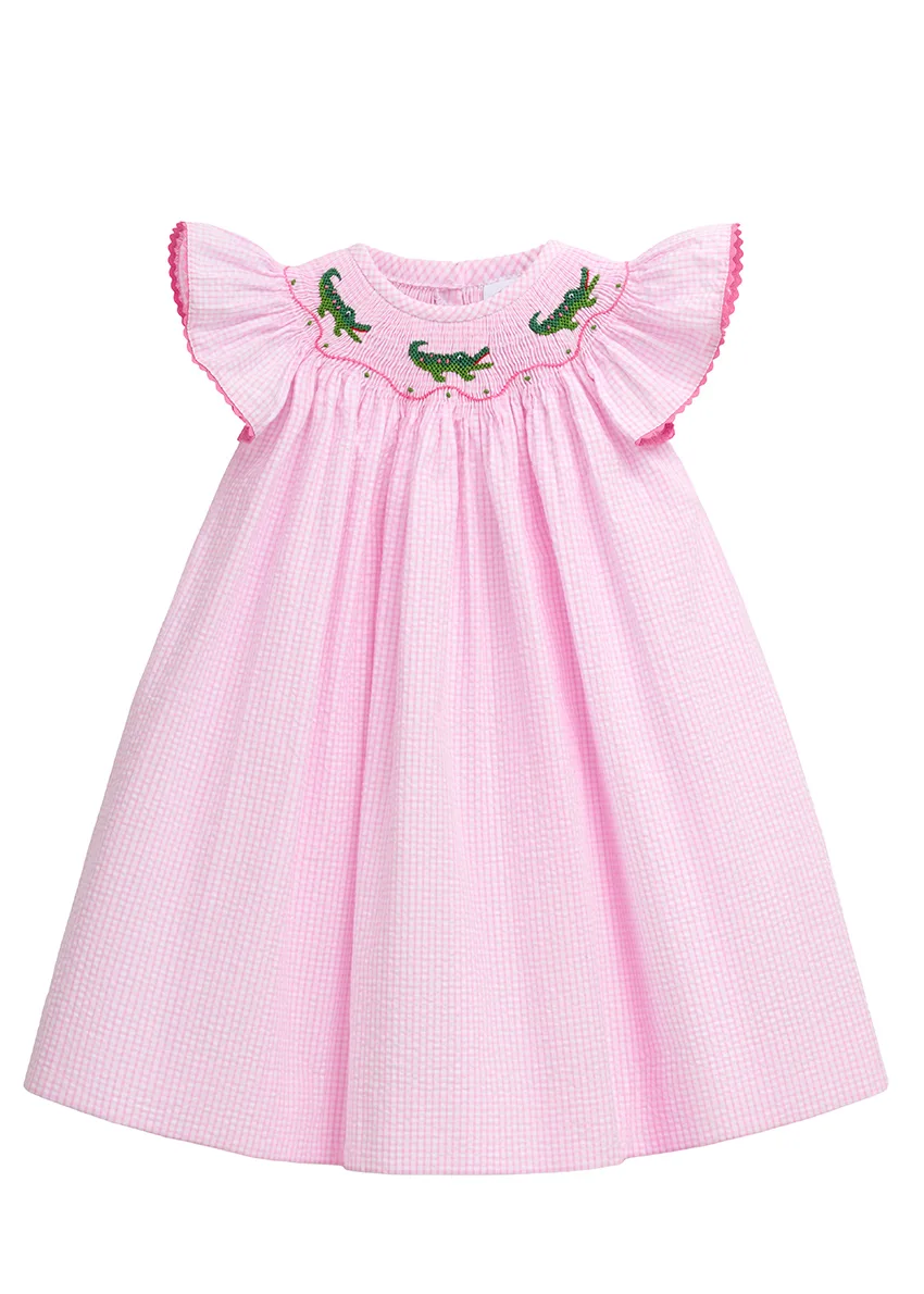 Pink gingham seersucker bishop dress with smocked alligator yoke and flutter sleeves, flat lay on white
