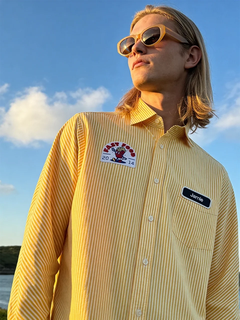 AI model photography of a man in a yellow striped shirt with an embroidered patch and name tag