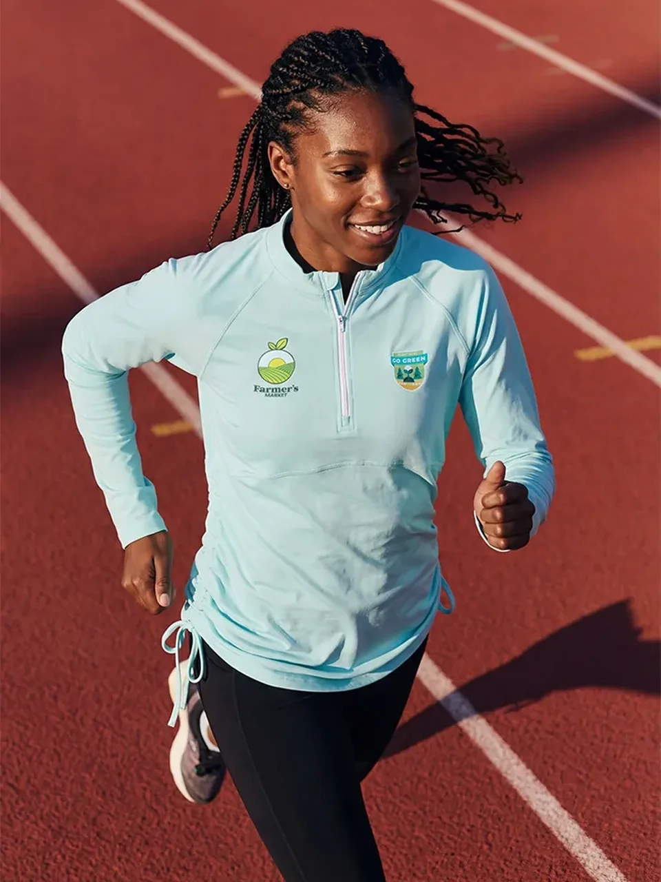 AI model photography of a runner in a light blue half-zip top with embroidered logos on a track