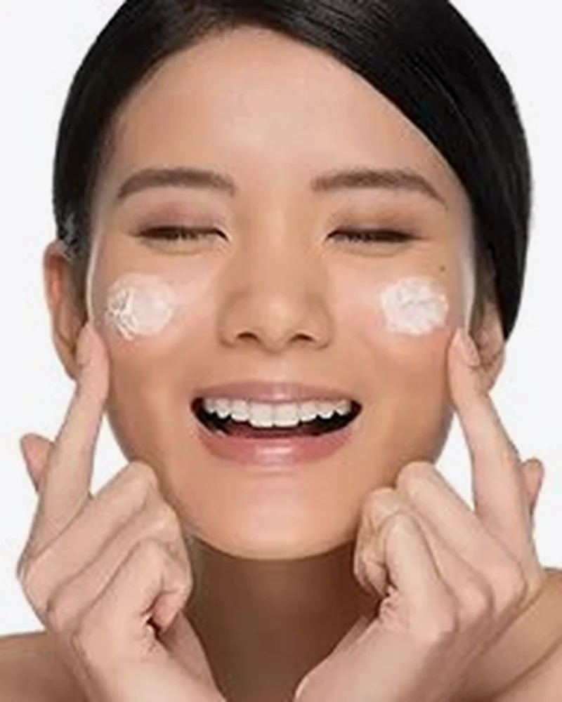 Smiling model with face cream on her cheeks