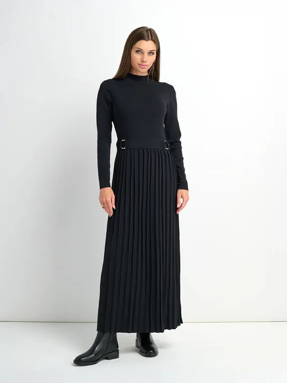 Model in a black knit top and pleated maxi skirt with a belted waist