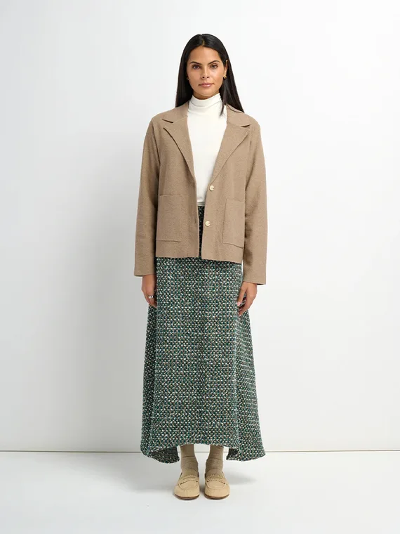 Model in a camel knit jacket over a green tweed midi skirt, full-length studio shot