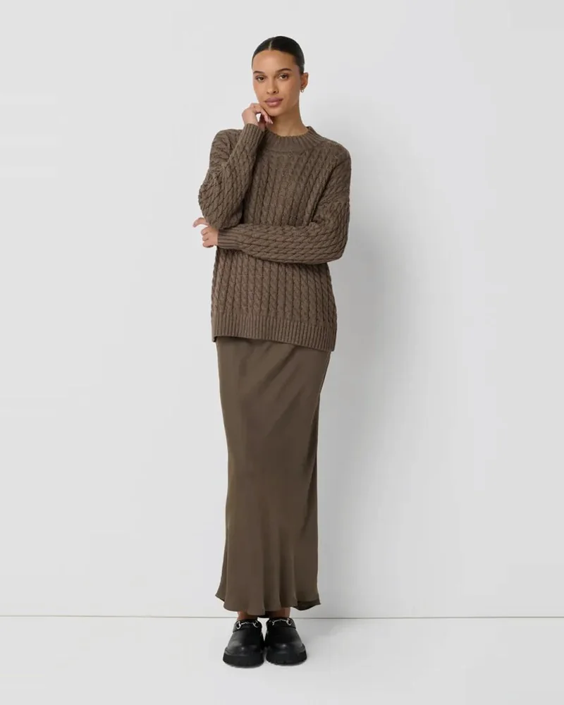 Model in a brown cable-knit sweater, satin maxi skirt and black loafers