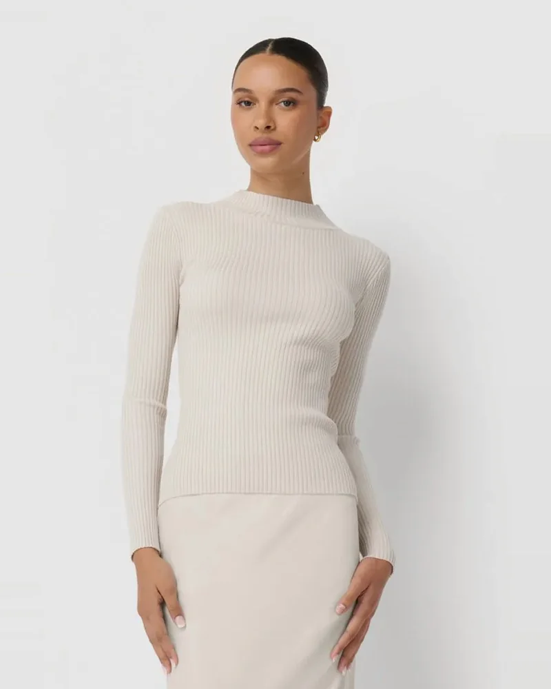 Model in a cream ribbed mock-neck sweater and satin skirt