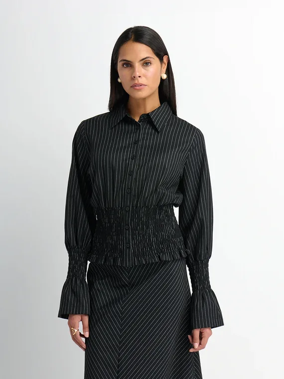 Model in a black pinstripe shirt with a smocked waist and matching pinstripe skirt