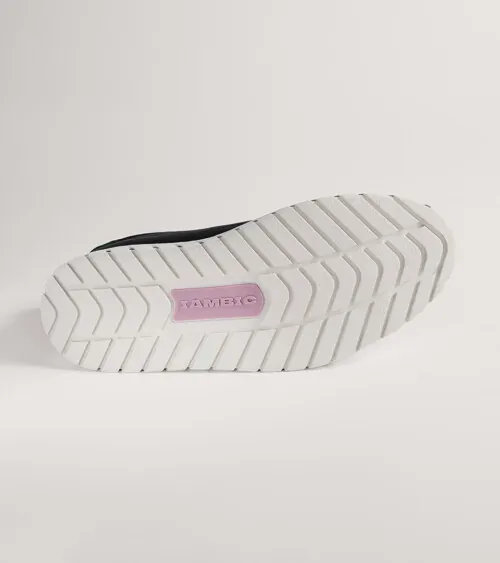 White platform sneaker photographed from below showing the patterned sole, on grey background, detail product photography