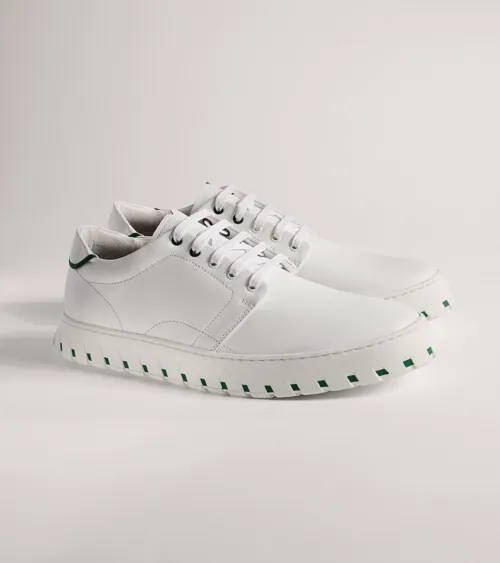 White leather low-top sneaker with white platform sole shown in side profile on grey background, studio product photography