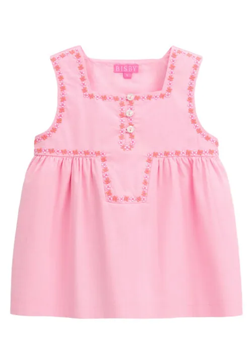 Flat lay photography of a pink sleeveless girls' dress with floral embroidered trim and button placket