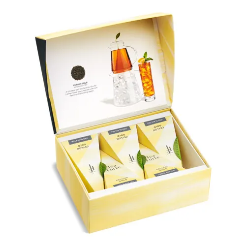 Product photography of an open yellow tea sampler gift box with black tea infusers and iced tea imagery on the lid