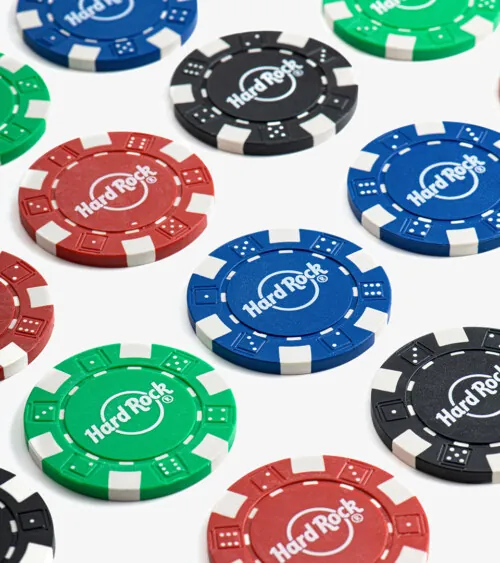 Scattered poker chips in red, blue, green, and black photographed close-up on white background, detail product photography