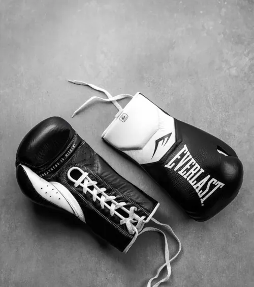 Pair of black and white boxing gloves styled on a gray concrete surface, lifestyle product photography