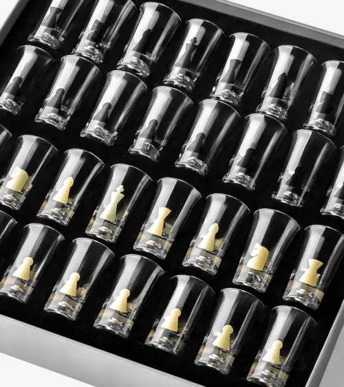 Set of chess-piece shot glasses arranged in a tray photographed overhead, studio product photography