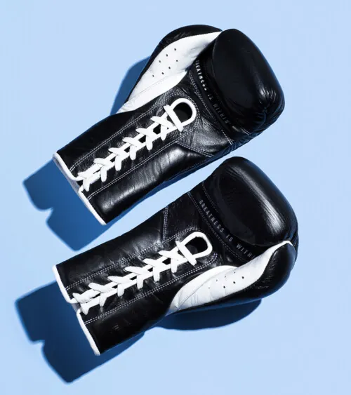 Pair of black leather boxing gloves photographed top-down on blue background, advertising product photography